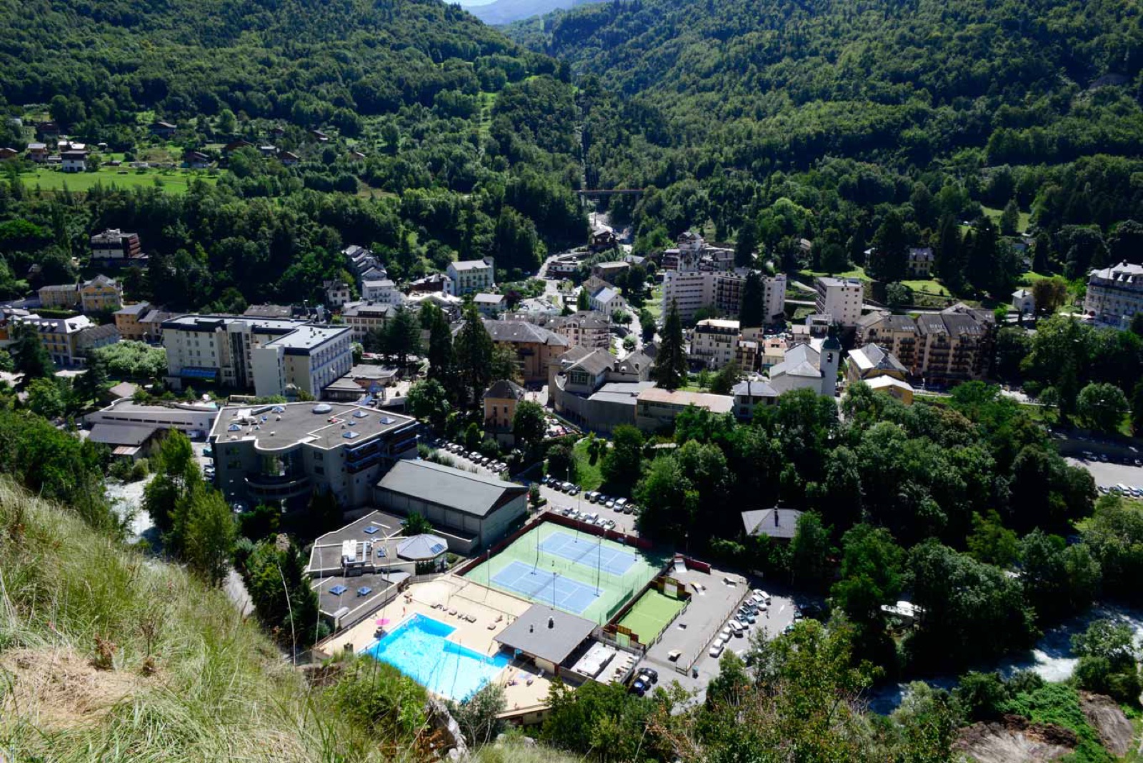 Vue aérienne de Brides-les-Bains en été : piscine, tennis et village au cœur de la Vanoise